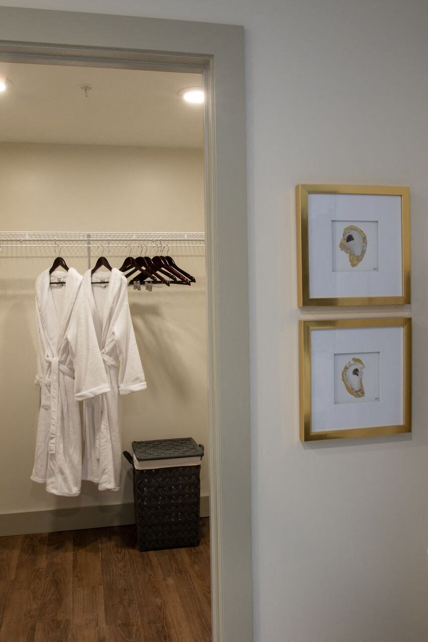 a bathroom with white robes and pictures on the wall