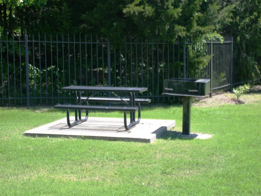 a picnic table and a barbecue grill in a park