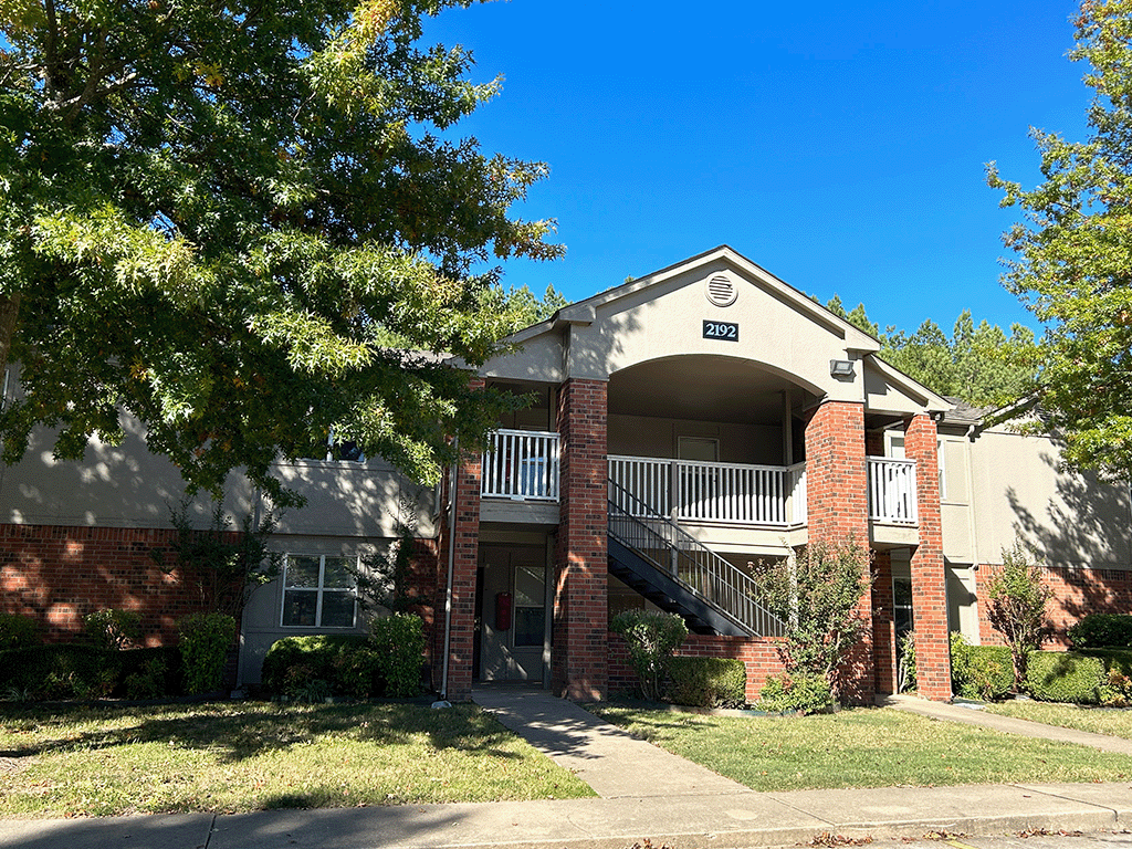 a brick house with a balcony and a tree