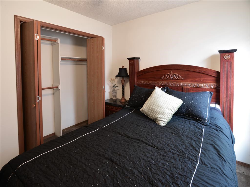 a bedroom with a bed with a black comforter and pillows