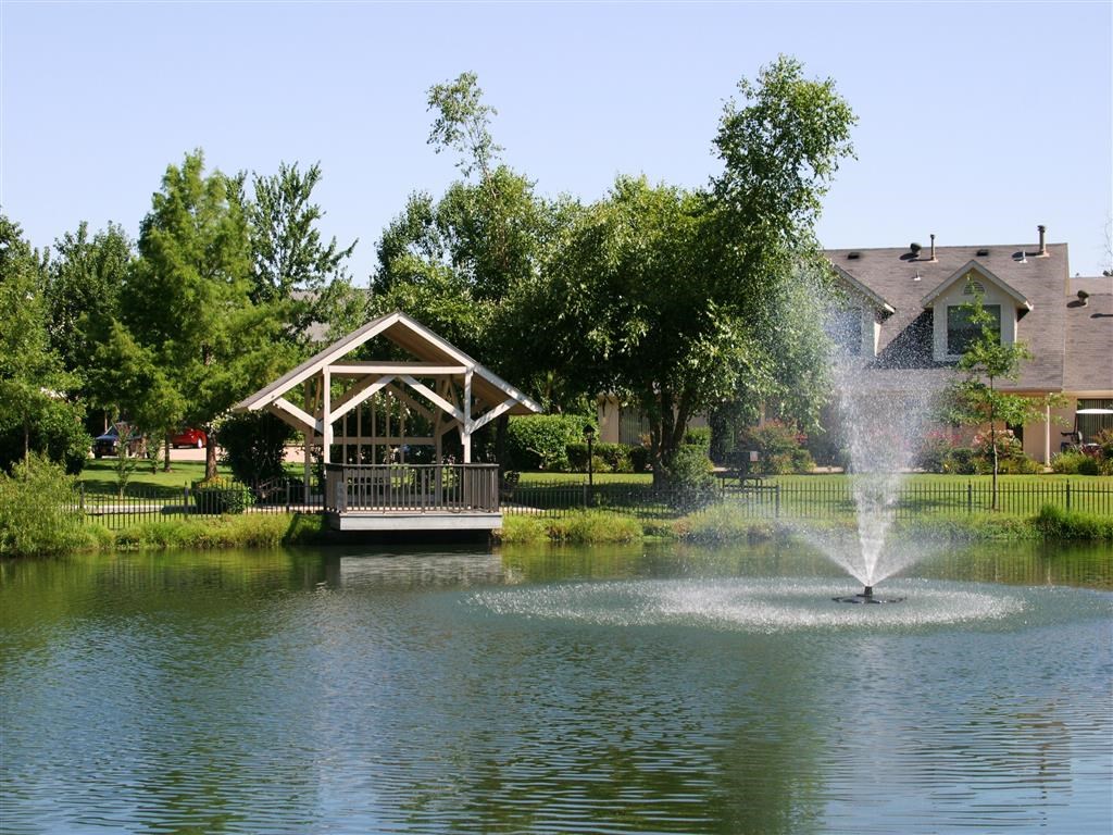 a fountain in the middle of a lake with a gazebo