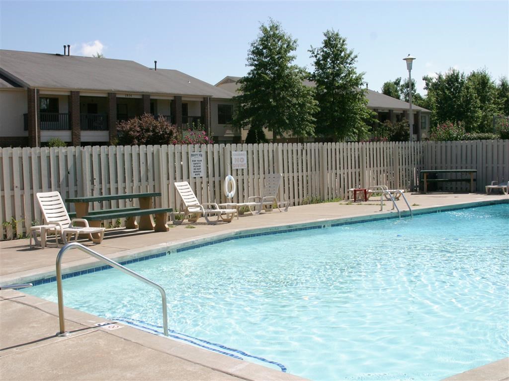 a swimming pool with chairs and a fence around it