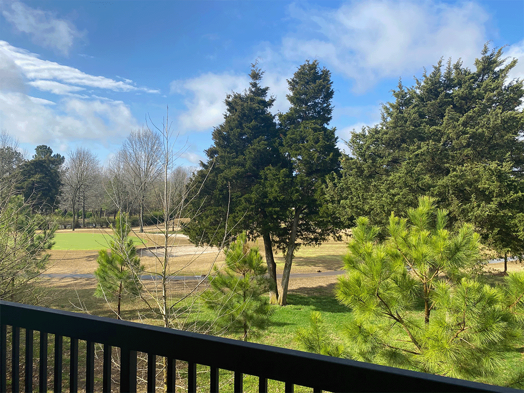 a view of the golf course from the balcony of a cabin