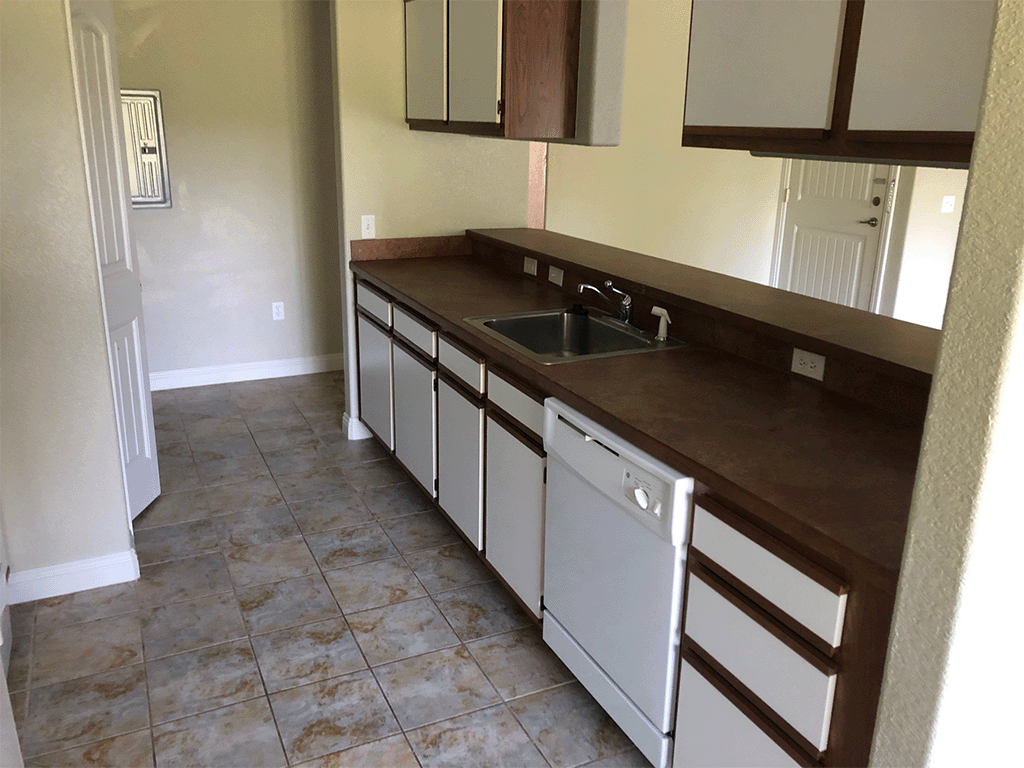 an empty kitchen with a sink and a counter top