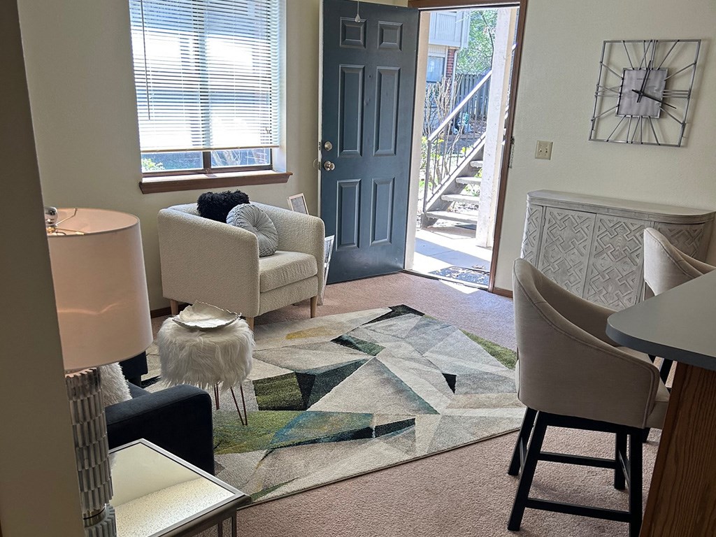 a living room with two chairs and a rug in front of a door
