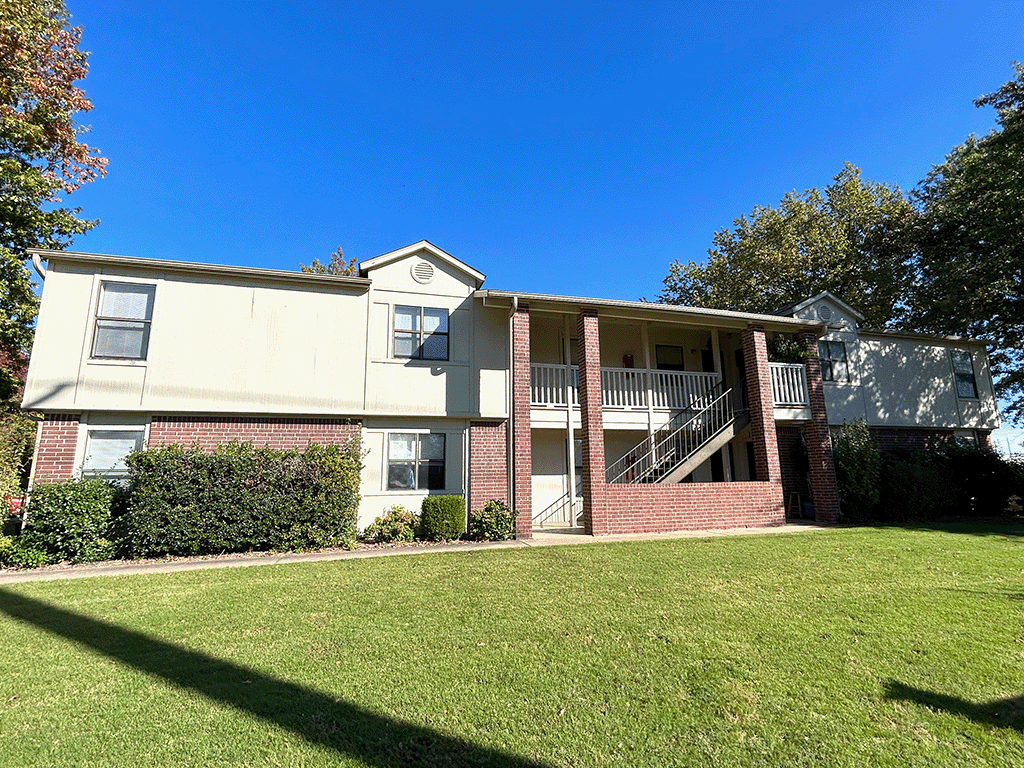 an exterior view of an apartment building with a green lawn