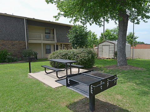 a picnic area with a table and a grill in front of an apartment building