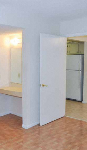 an empty kitchen with a refrigerator and an open door