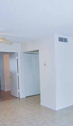 an empty living room with white walls and a tile floor