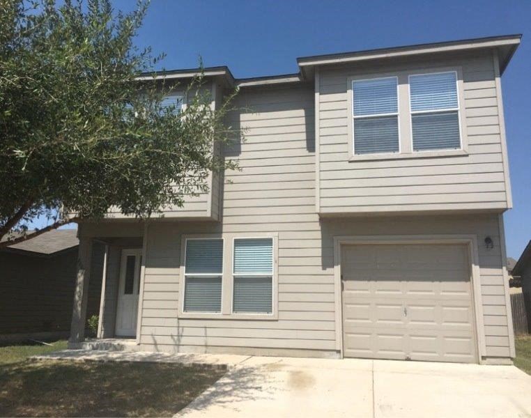 a white house with two garage doors and a tree