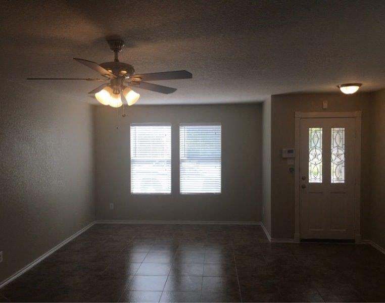 a empty living room with a ceiling fan and a door