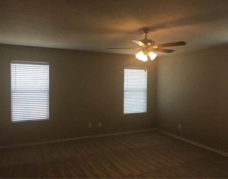 an empty room with a ceiling fan and two windows
