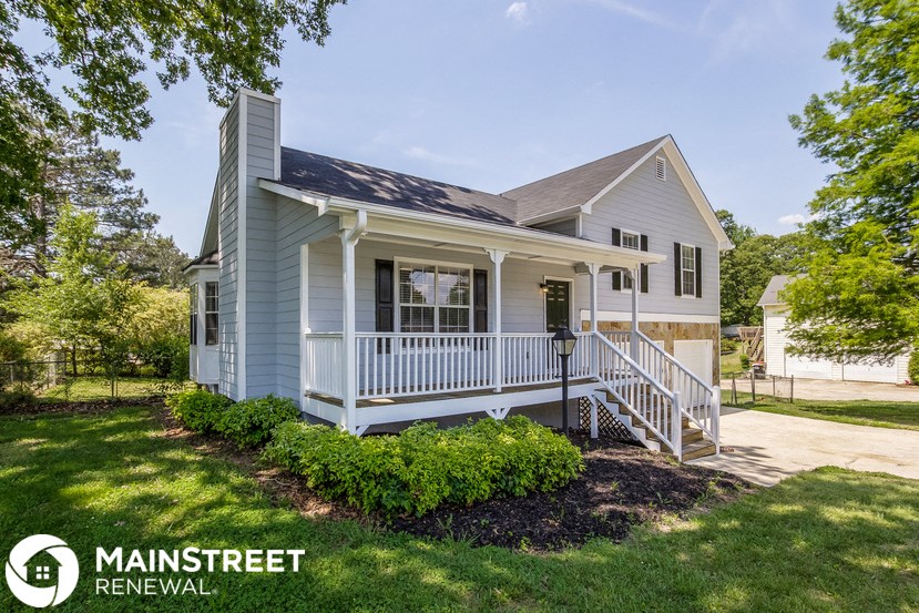 a small blue house with a front porch and a lawn
