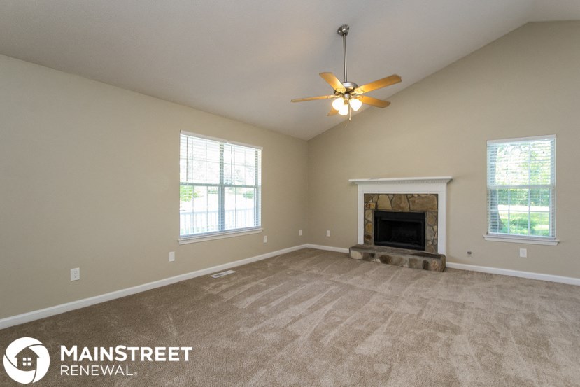 a living room with a fireplace and a ceiling fan