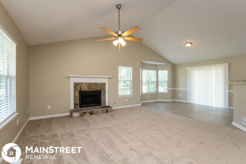 a living room with a fireplace and a ceiling fan