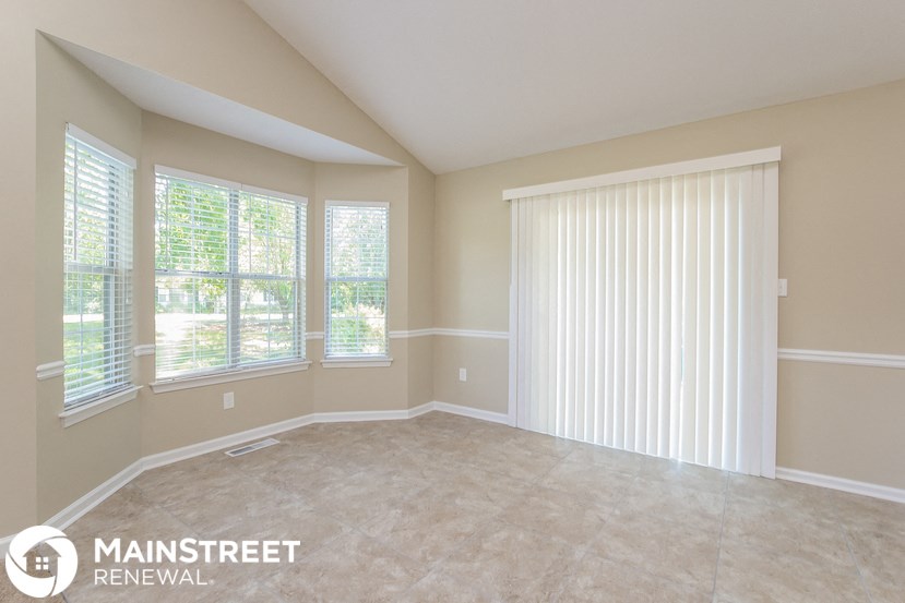 an empty living room with a large window and blinds