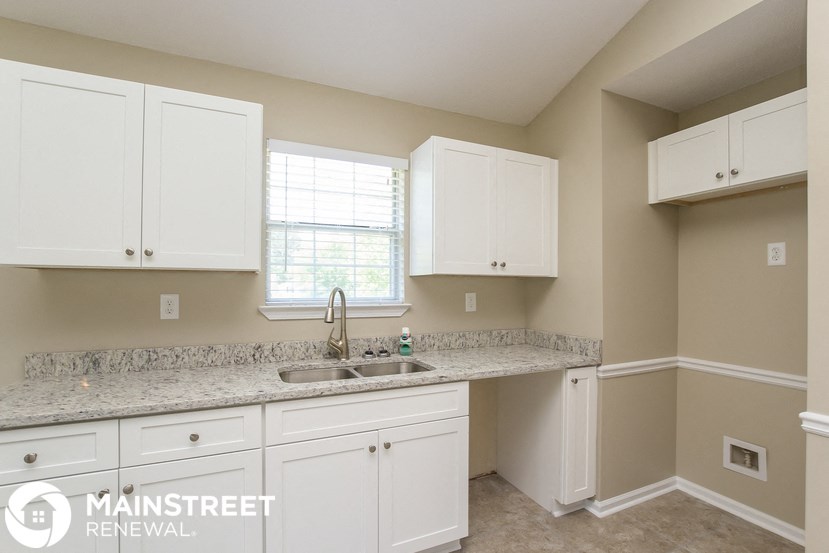 a kitchen with white cabinets and granite counter tops and a sink