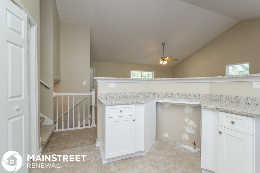 a kitchen with white cabinets and a counter top and a staircase