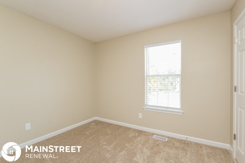 a bedroom with beige carpet and a window