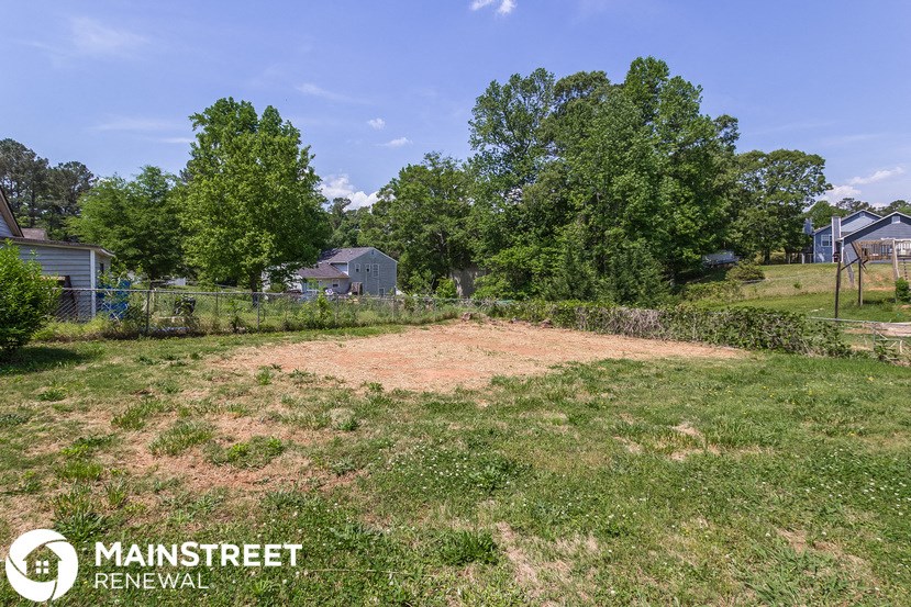 a backyard with a dirt field and a fence and trees