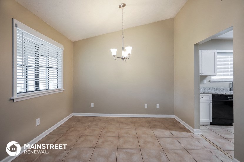 the dining room and kitchen of a home with beige walls and tiled floors
