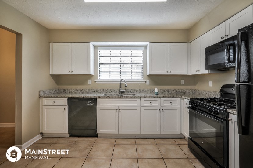 a kitchen with white cabinets and black appliances