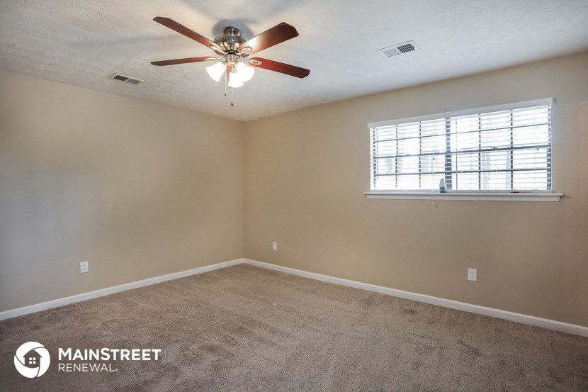 the master bedroom has a ceiling fan and a window