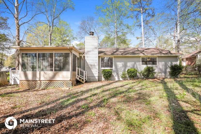a small white house with a yard and trees
