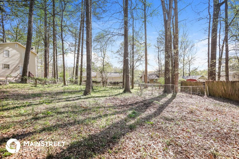 a backyard with trees and a fence and a house