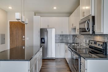 Kitchen with dark countertops, matching stainless steel appliances and white cabinets at Ascend at Woodbury in Woodbury, MN
