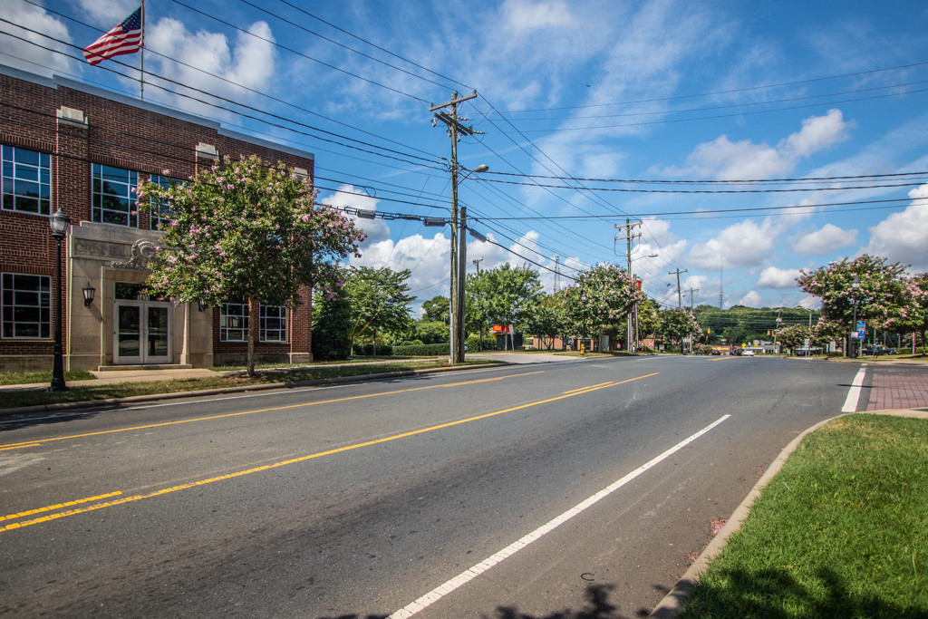 an empty street in front of a building with an flag on the corner