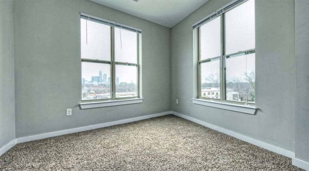 an empty room with three windows and a carpet