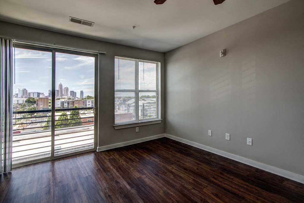 the living room of an apartment with wood floors and a view of the city