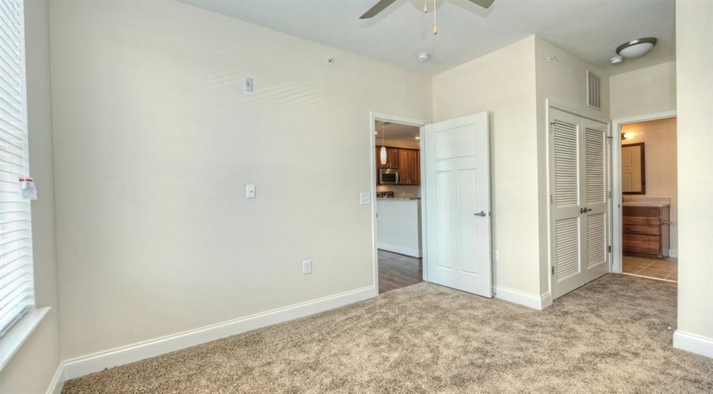 an empty living room with a closet and a door to a kitchen