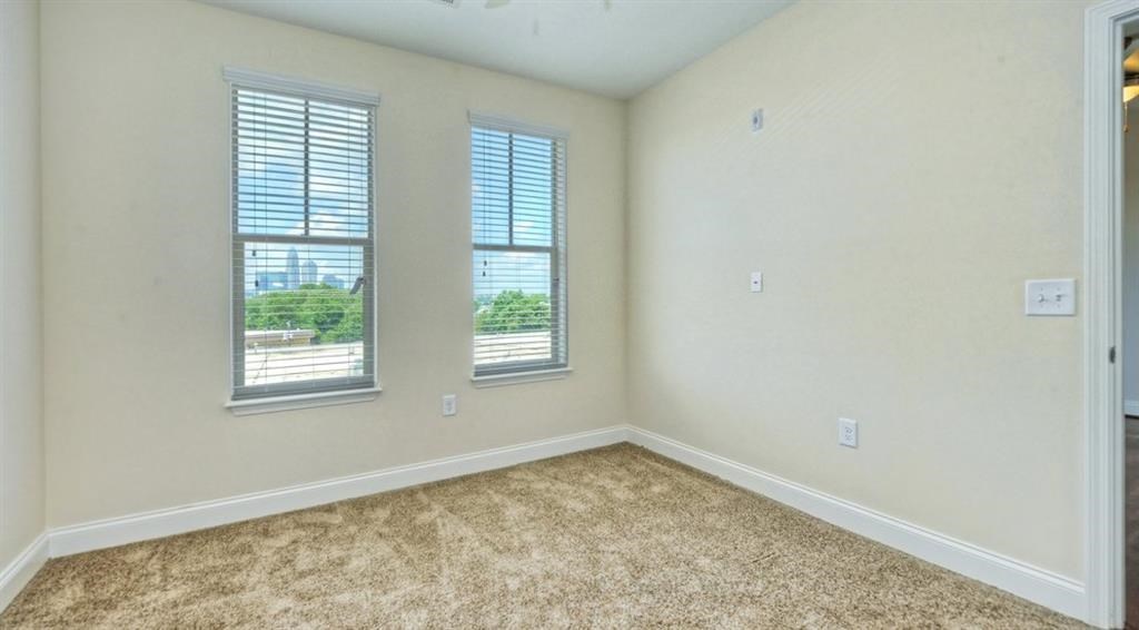 an empty bedroom with two windows and a carpeted floor
