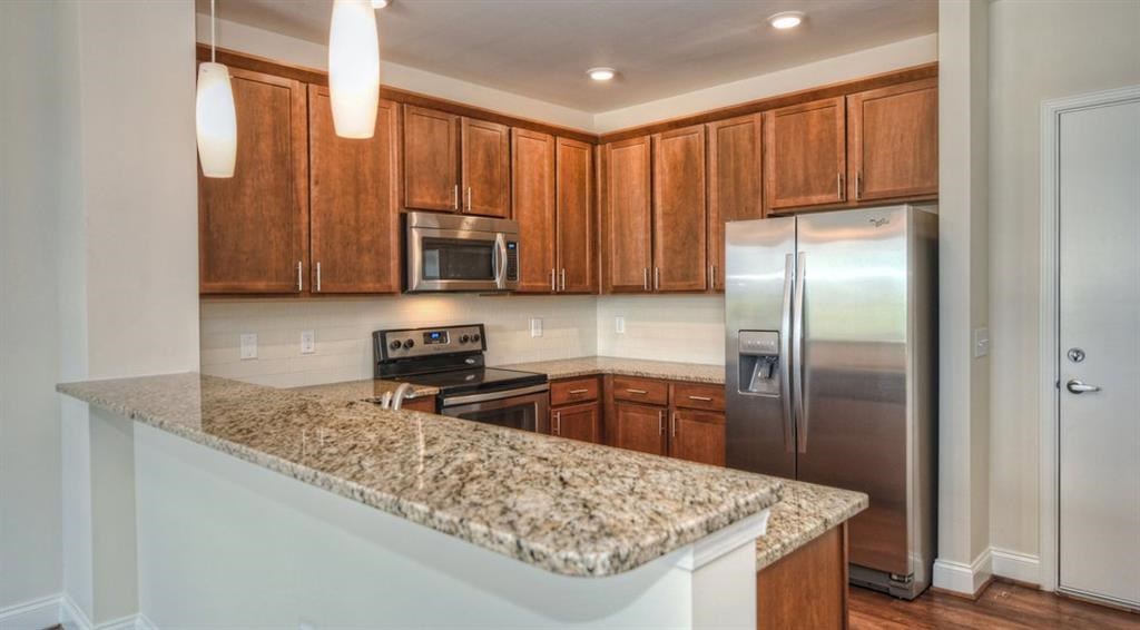 a kitchen with granite counter tops and a stainless steel refrigerator