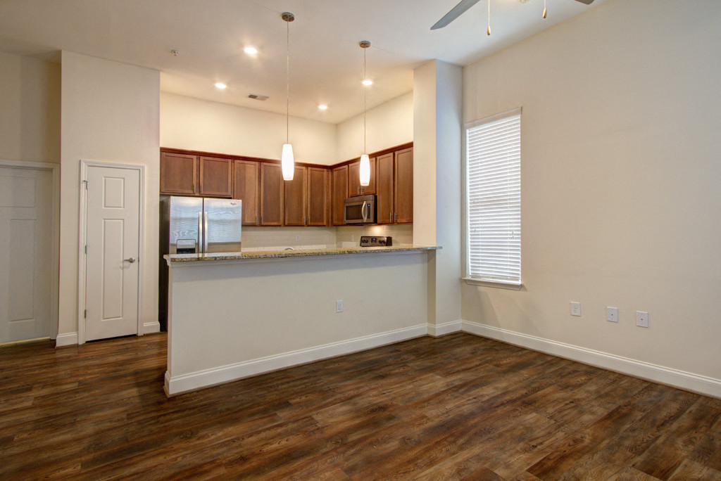 an empty living room with a kitchen and a door