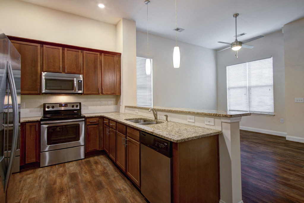 an empty kitchen with wooden cabinets and stainless steel appliances