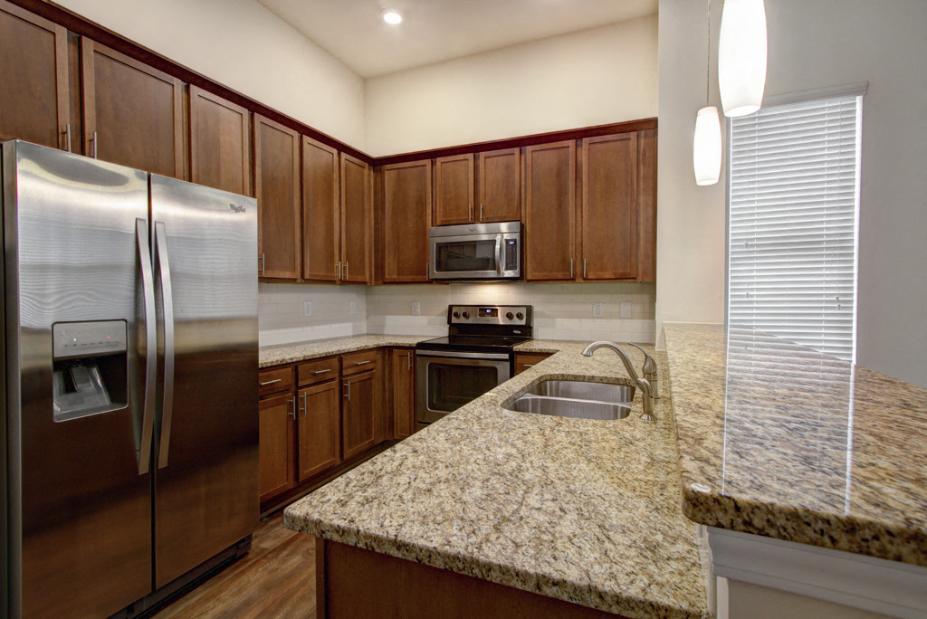 a kitchen with granite counter tops and a stainless steel refrigerator