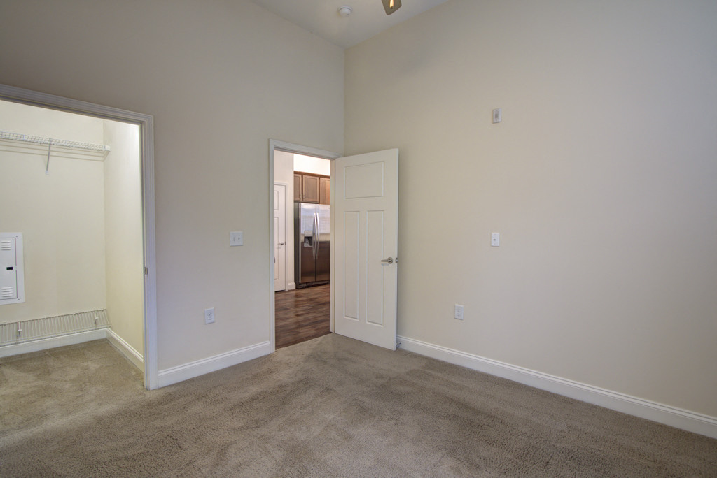 a living room with carpet and a door to a bedroom