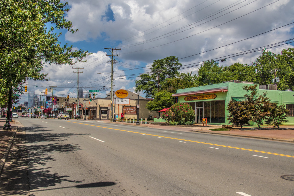 a city street with stores and trees on the side of the road