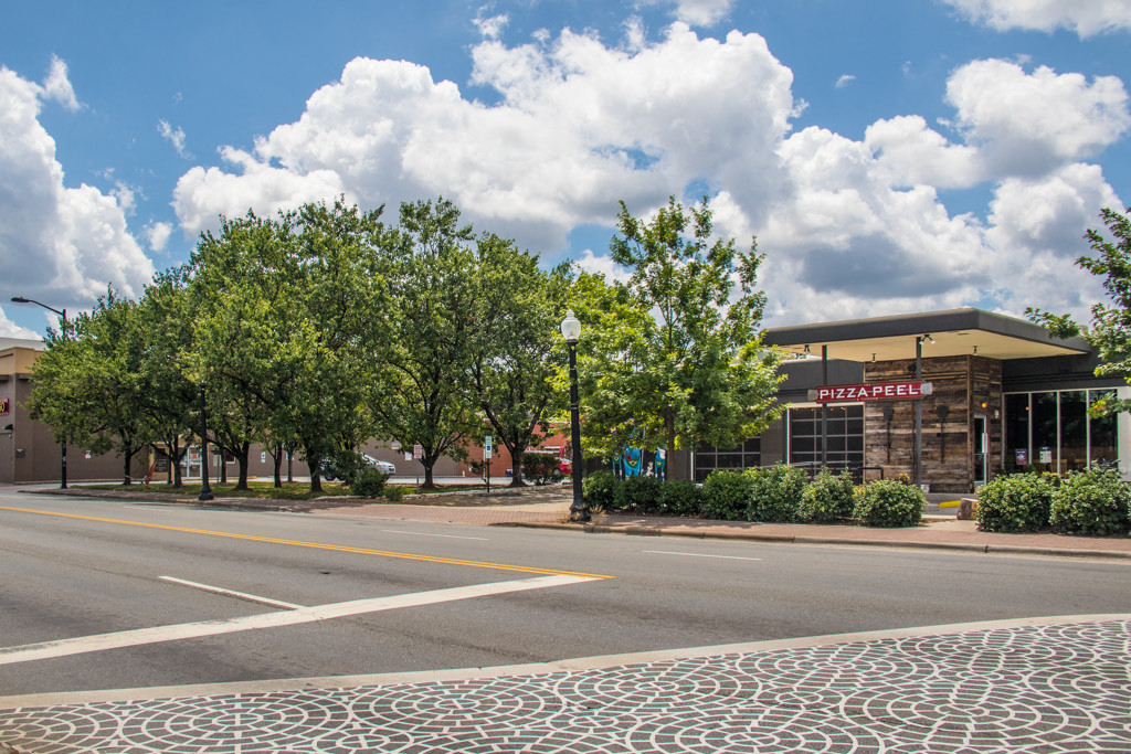 an empty street in front of a building with trees
