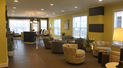 a living room with yellow walls and chairs and a bar