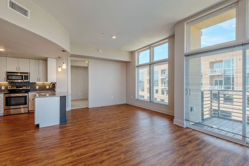 an empty living room with a large window and a kitchen
