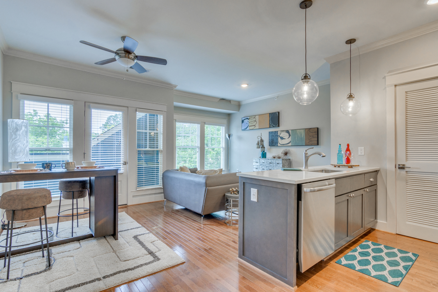 a living room with a kitchen and a ceiling fan