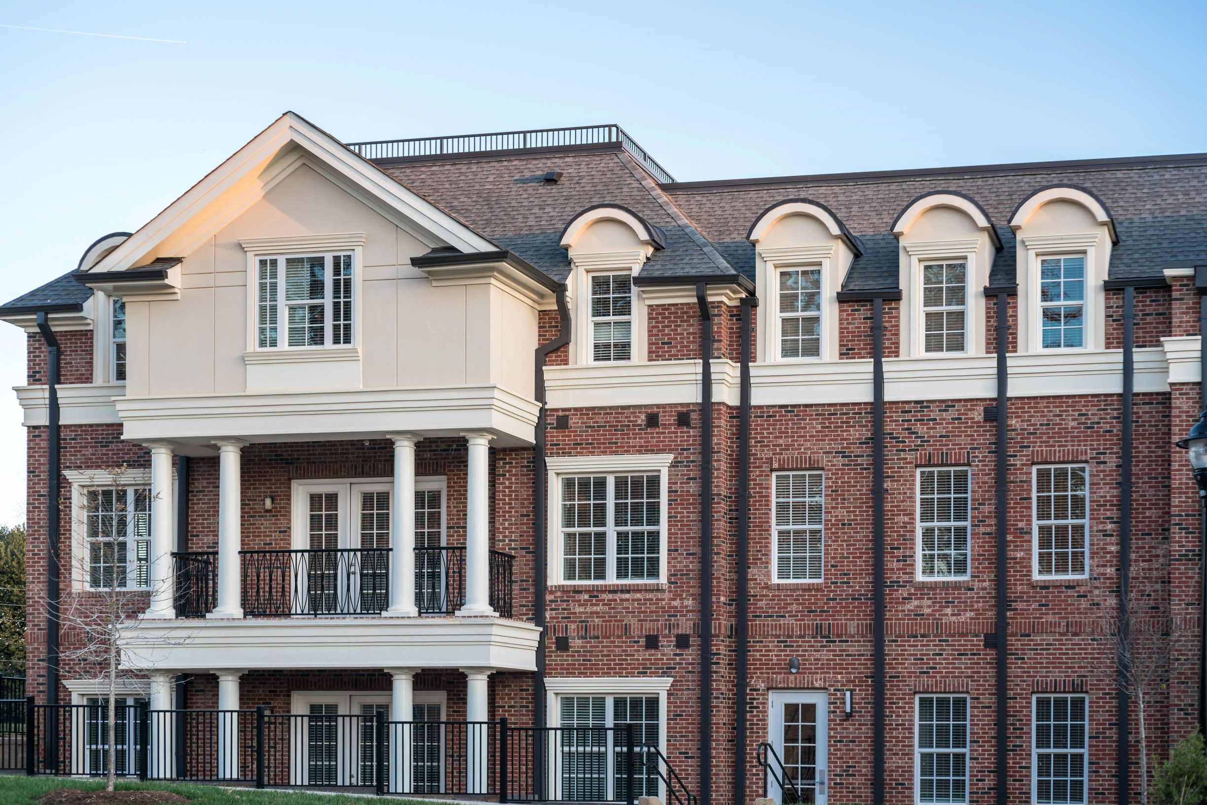 a red brick building with white columns and a black fence