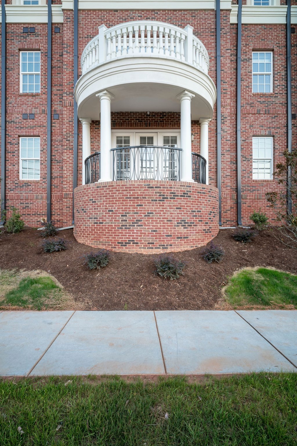 the front porch of a brick building with a balcony