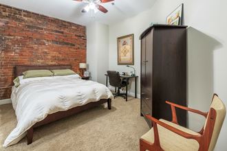a bedroom with a bed and a brick wall    and a dresser
