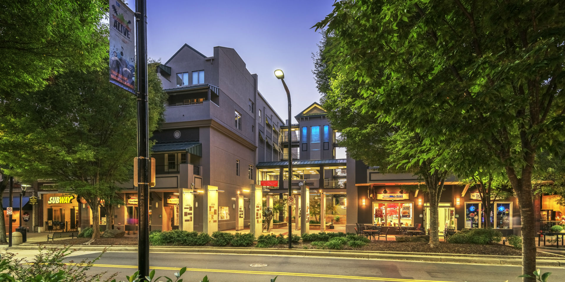 a city street at night with buildings and trees