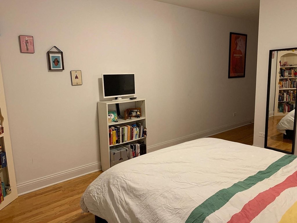 a bedroom with a bed and a tv on a shelf